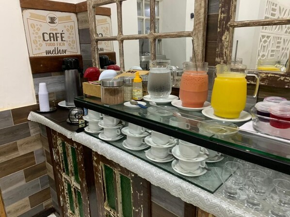 Zona de bar con una máquina de café, diferentes recipientes para bebidas y un espejo que refleja el espacio.