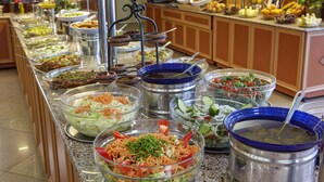 Un bufé con diversas opciones de comida, incluyendo ensaladas, frutas y otros platos.