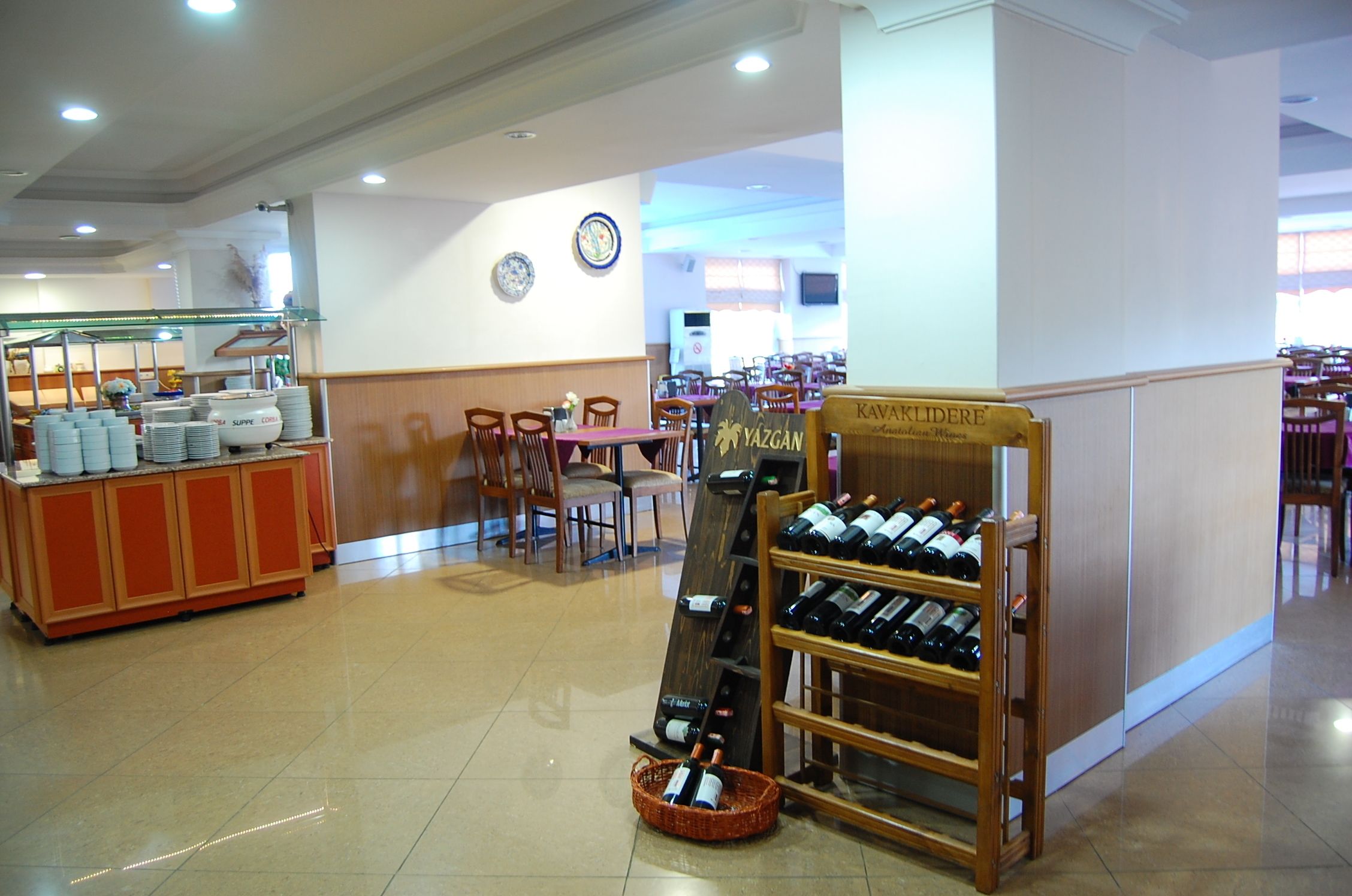 A restaurant interior with a wine display, dining tables, chairs, and a buffet area.
