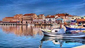 Un muelle con barcos amarrados, edificios con tejados rojos y un cielo despejado.