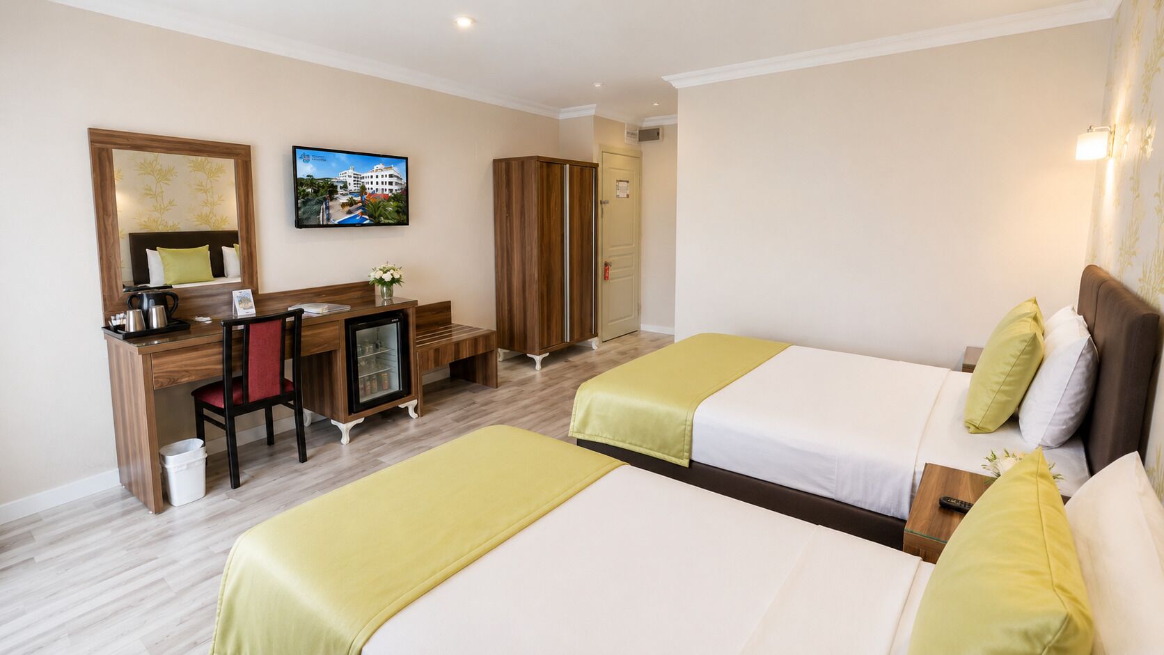 A hotel room with two beds, a desk, a chair, a television, and a wardrobe.