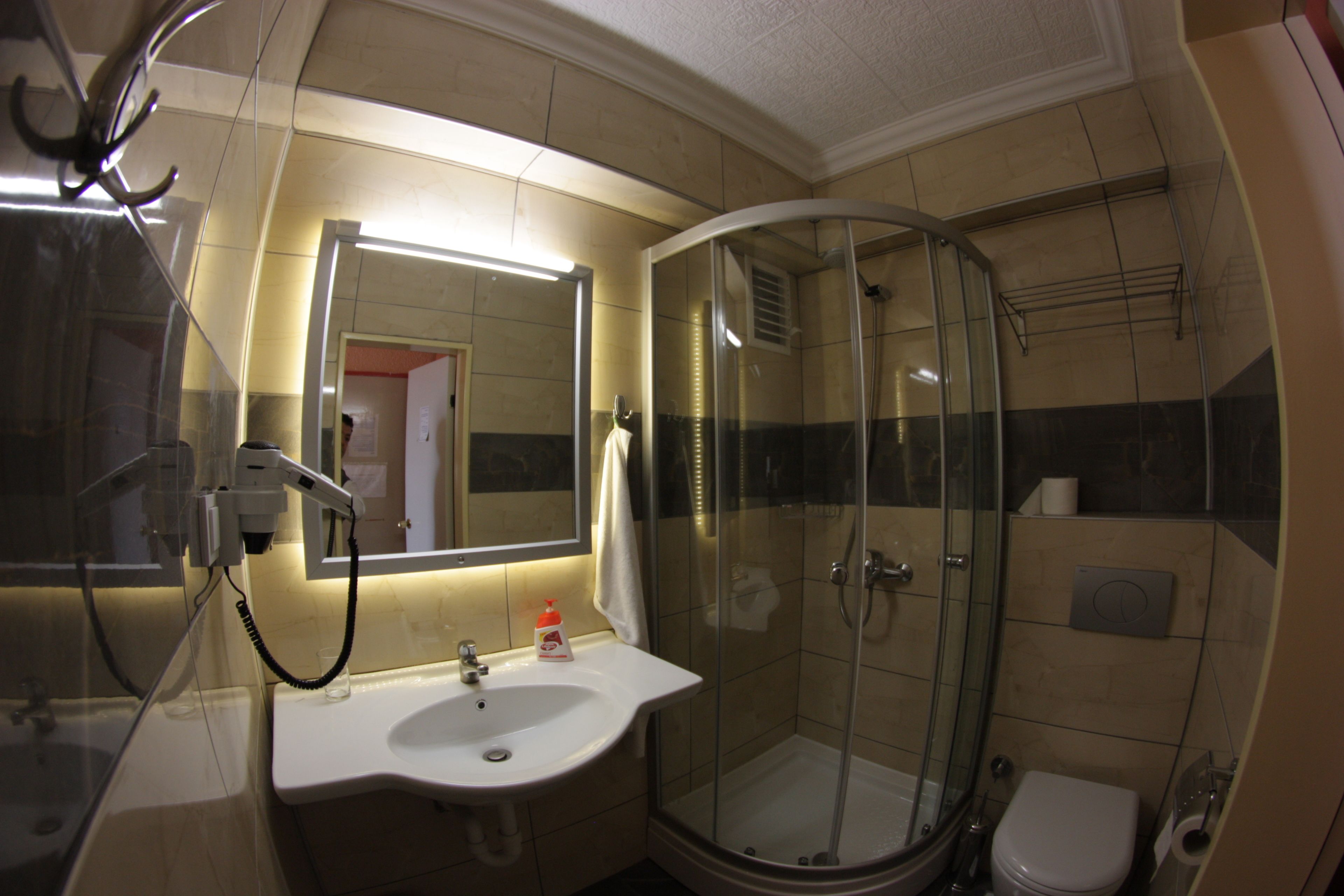 A bathroom with a glass-enclosed shower, a sink with a mirror, and a toilet.