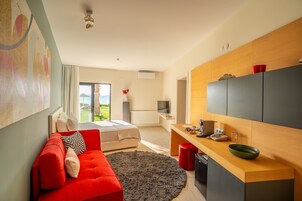 Una habitación moderna con sofá rojo, escritorio de madera, ventana grande y vistas al exterior.