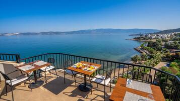 Una terraza con mesa y sillas de madera que da a un mar tranquilo.