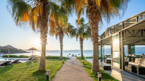 A pathway leading to a modern outdoor seating area with a view of the sea. - Med-Inn Hotel (Milas)