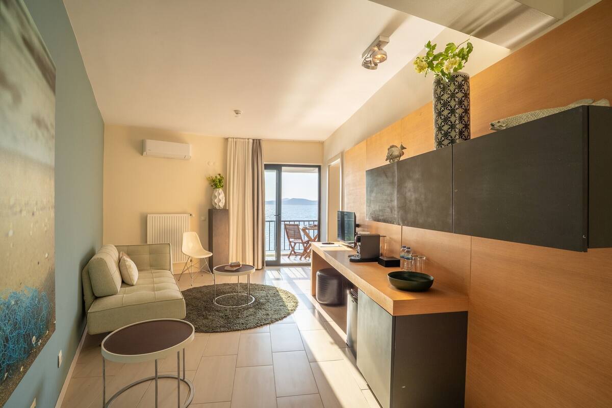 A modern living room with a sofa, a small round table, and a view of the outdoors through a large window.