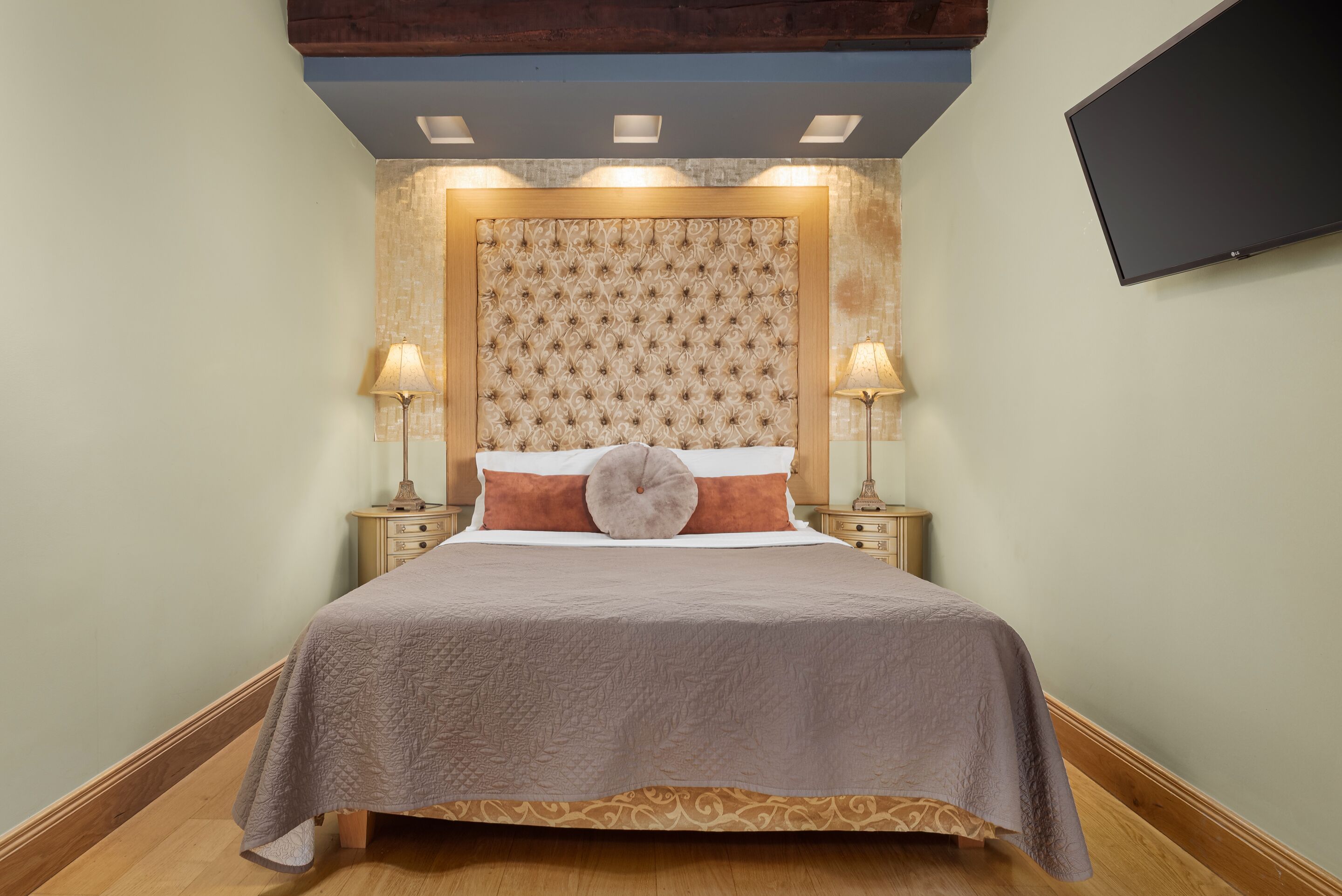 A neatly made bed with a patterned bedspread, two bedside lamps, and a decorative headboard.
