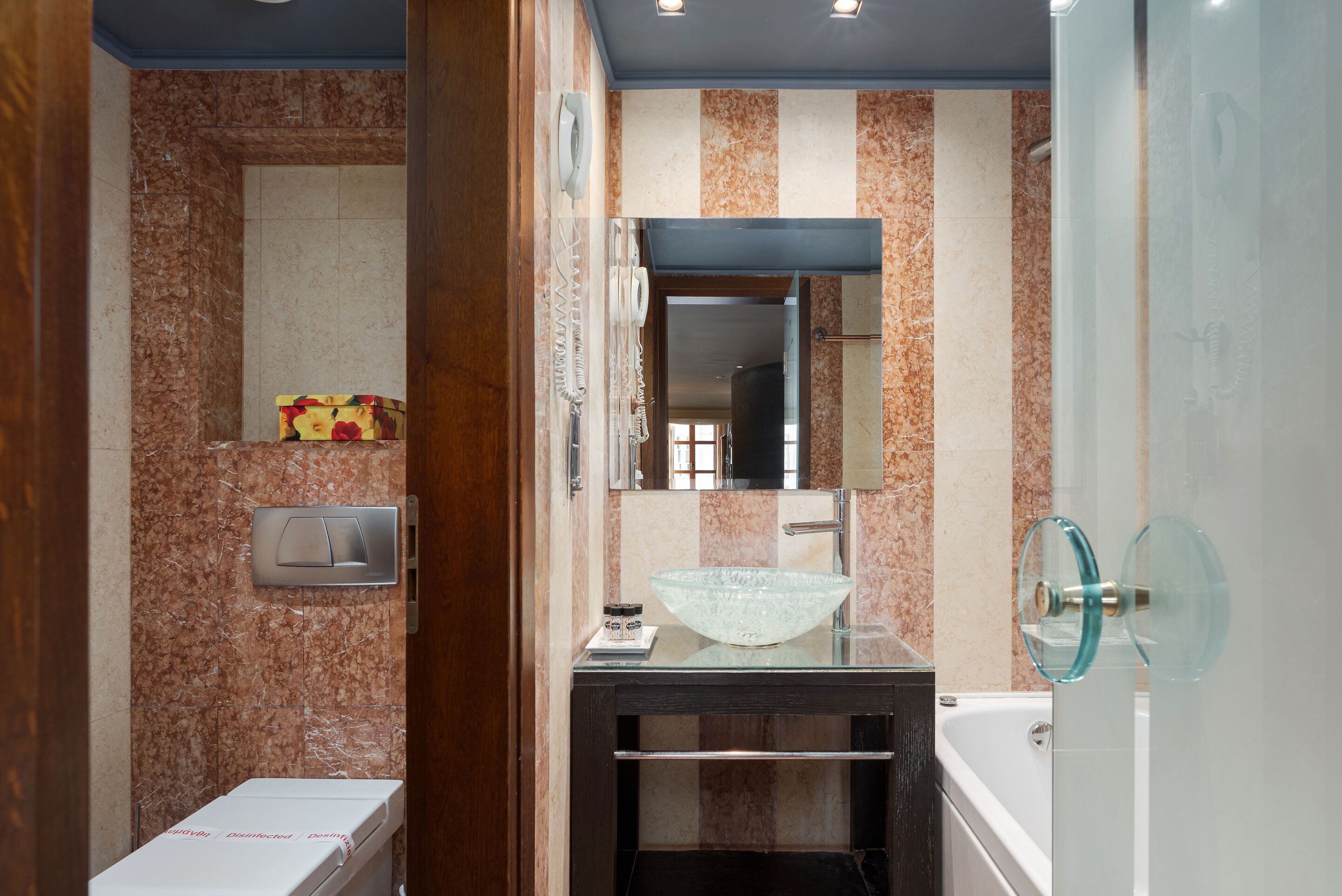 A bathroom with a glass sink, a mirror, and a shower.