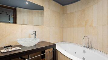 Een moderne badkamer met een grote glazen wasbak, een vrijstaand bad en een spiegel boven de wasbak.