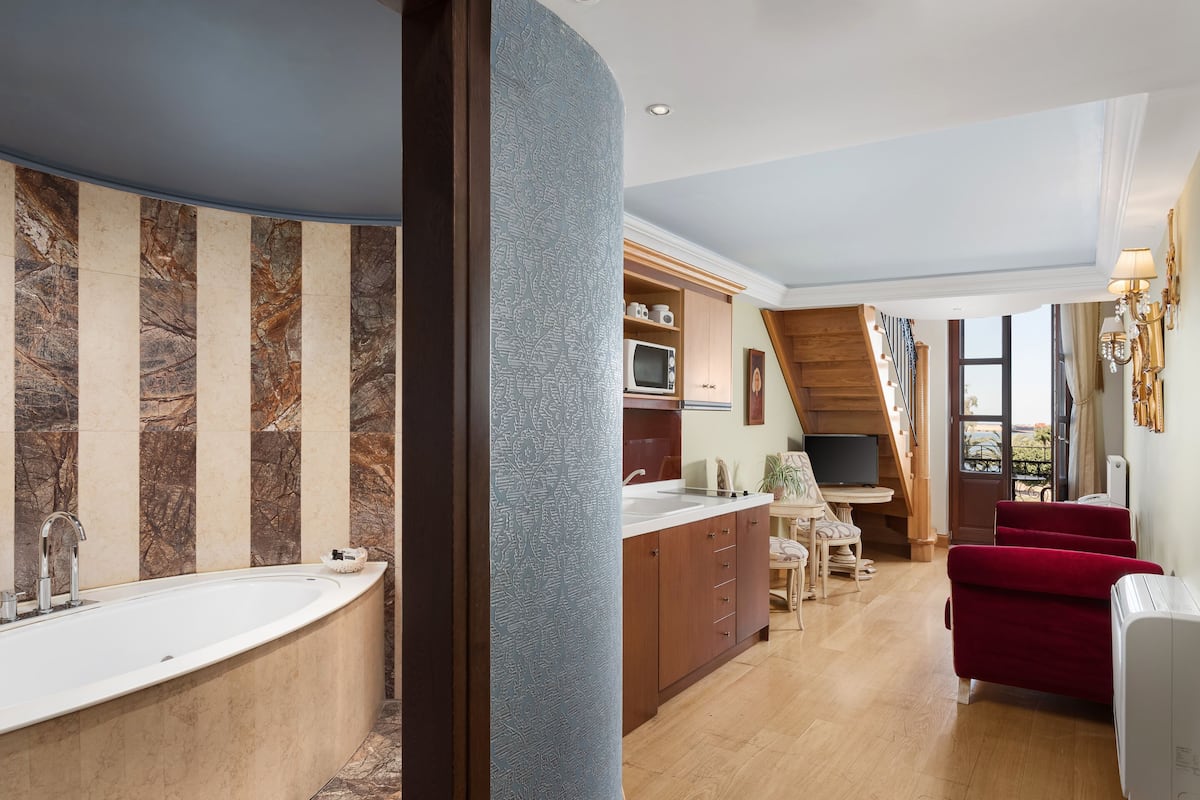 A modern kitchen with a built-in microwave, wooden cabinets, and a dining area with a red sofa and a table.