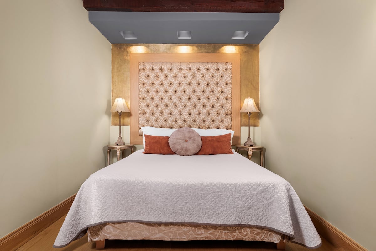 A neatly made bed with a tufted headboard, two bedside lamps, and a decorative pillow.