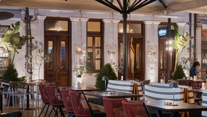 An outdoor dining area with wooden tables and chairs, potted plants, and a sign for 'Civititas'. - Civitas Suites Hotel (Rethymno)