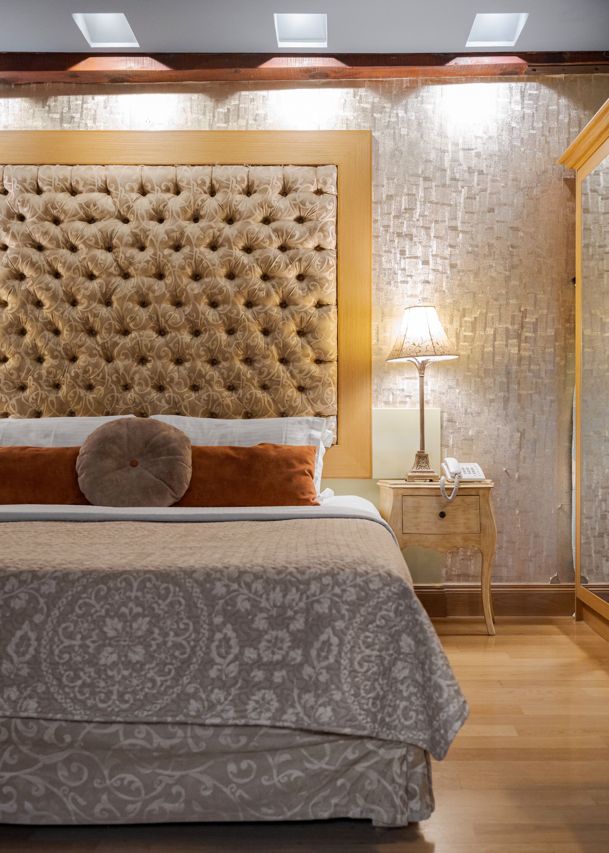 Ein Schlafzimmer mit einer gesteppten Kopfteile, einer Nachttischlampe und einem Holznachttisch.