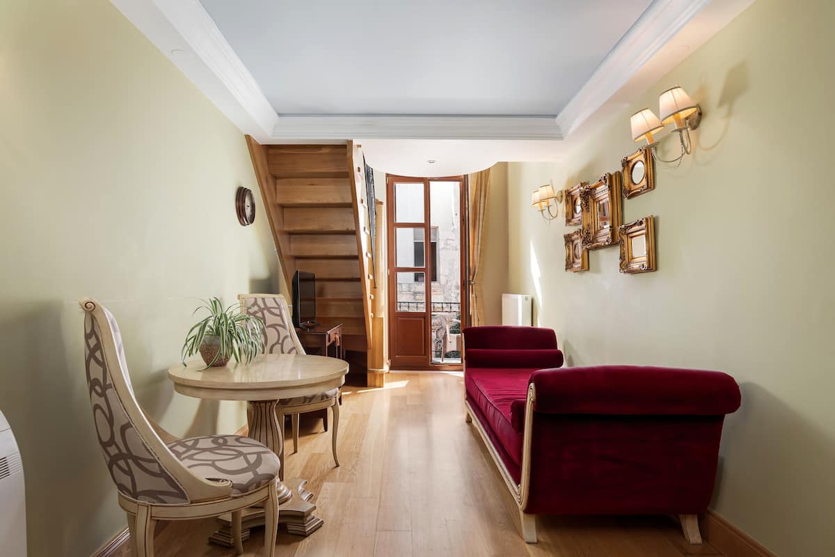 A dining area with a wooden staircase, a red sofa, and wall-mounted picture frames.