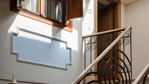A staircase with a wrought iron railing, wooden handrails, and a skylight above. - Civitas Suites Hotel (Rethymno)