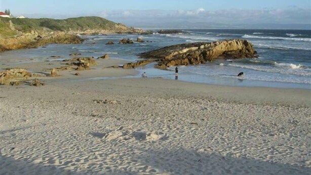 A beach with rocky outcrops, a sandy shore, and a clear sky. - Milkwood Lodge - Hermanus (Hermanus)