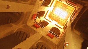 Une pièce dotée d’une cheminée centrale, de niches en arc de cercle et d’une grande fenêtre.
