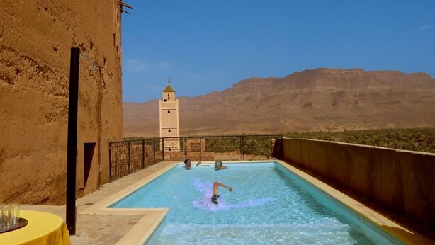 Une piscine offrant une vue sur une chaîne de montagnes et une tour en arrière-plan.