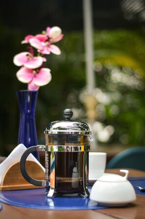 Une machine à café est posée sur une table, à côté d’un vase bleu et d’une théière blanche.