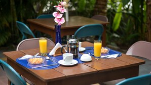 A dining table set with breakfast items, including a coffee pot, cups, and a fruit bowl. - Jardin Azul - Casa Hotel (Cali)