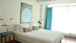 A bedroom with a bed, a nightstand, a poster on the wall, and a window with curtains. - Jardin Azul - Casa Hotel (Cali)