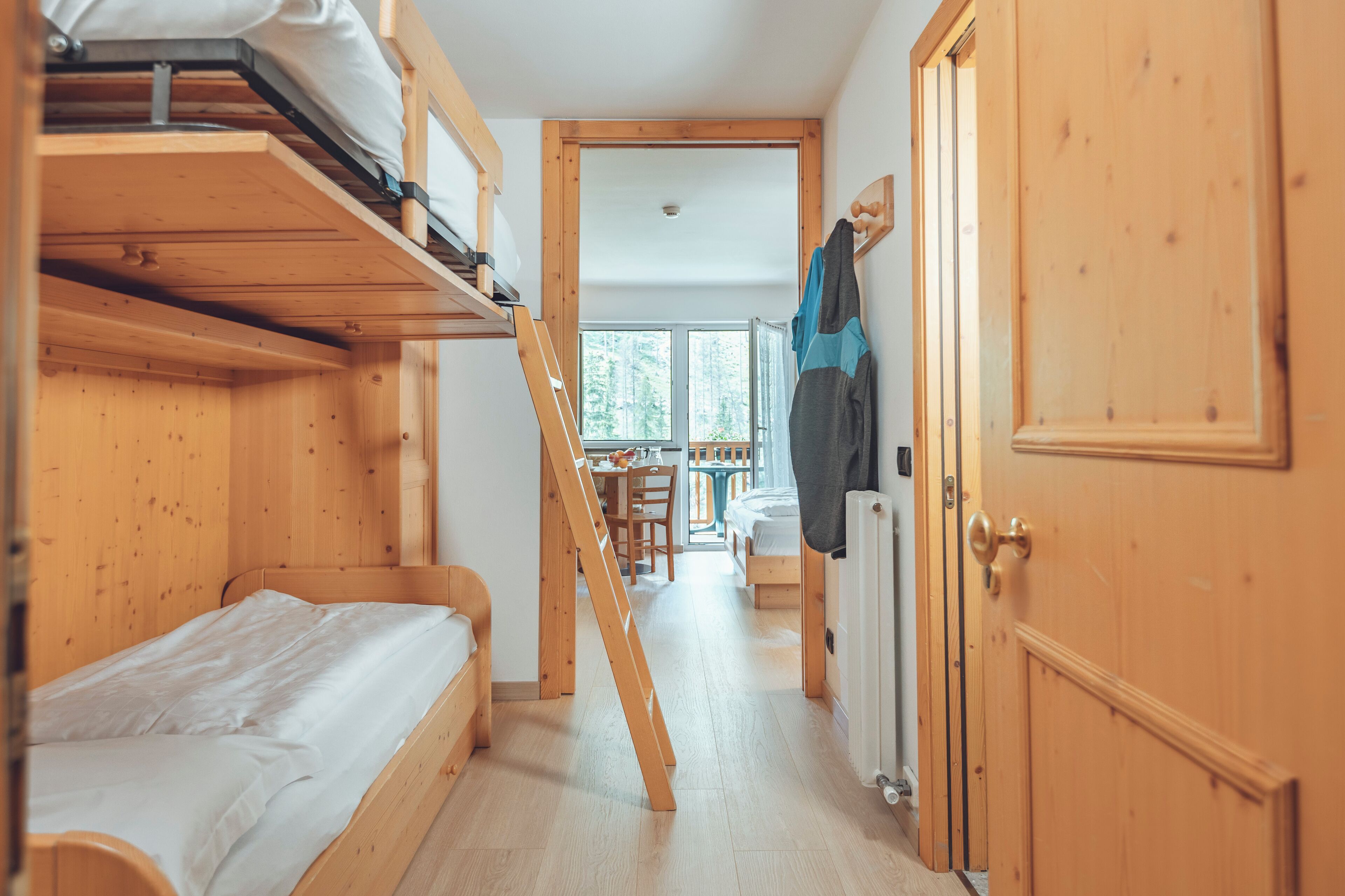 Una habitación con literas, una puerta de madera y vistas a un comedor.