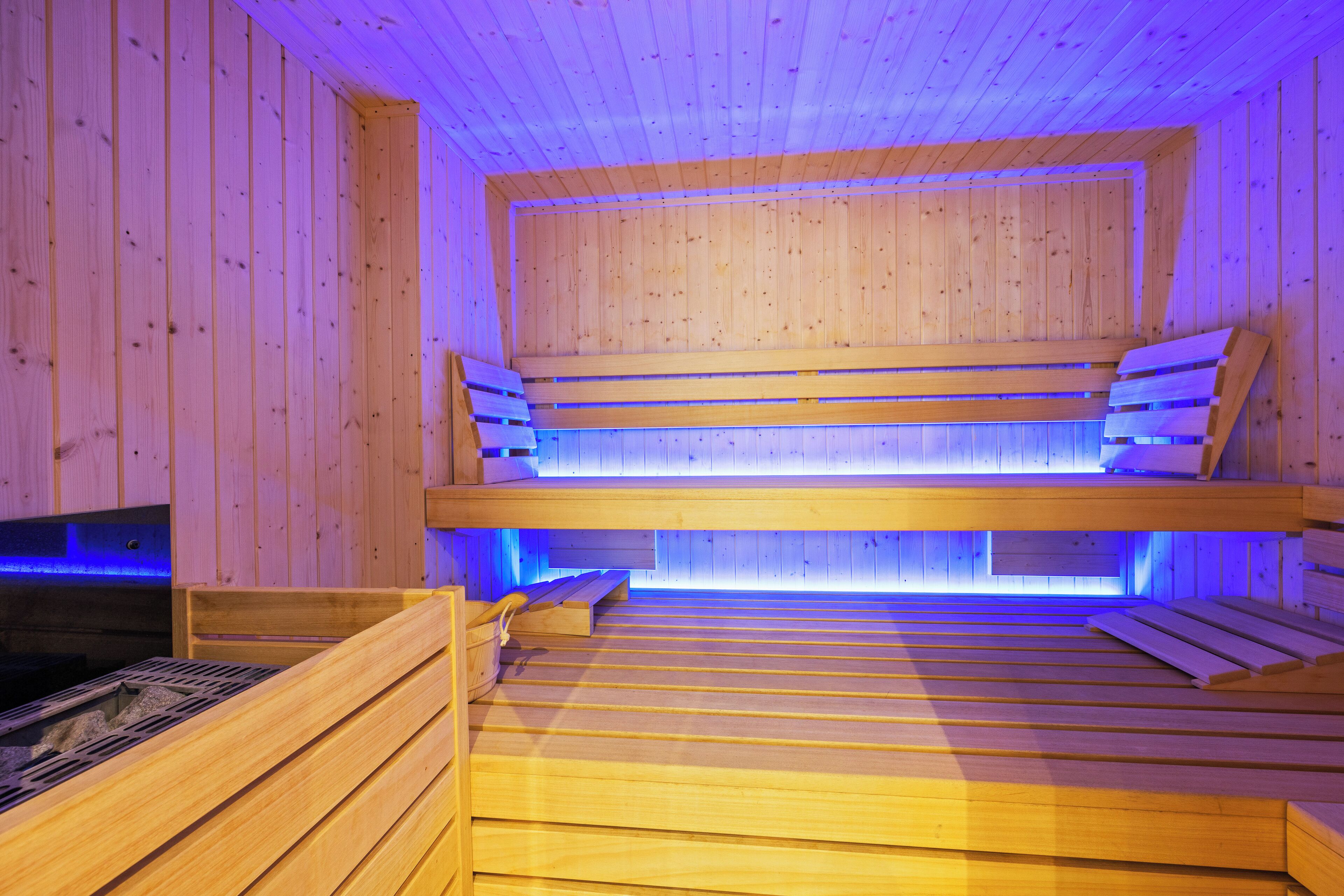 Eine Sauna mit Holzbänken und einem sichtbaren Heizaggregat.