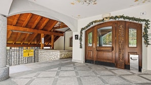Un hall d’entrée avec un sol à carreaux, un plafond en bois et un mur en pierre.