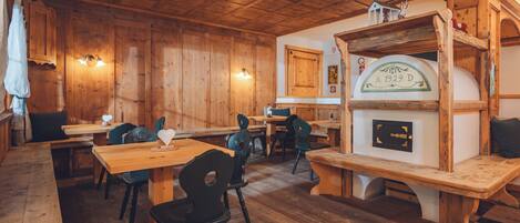 A wooden interior with tables and chairs, a fireplace, and a wooden ceiling.