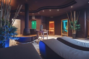 A spa room with two massage tables, a sauna, and a green door. - Aparthotel Princess (Canazei)