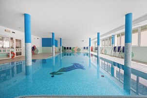Una piscina techada, sillones reclinables de piscina