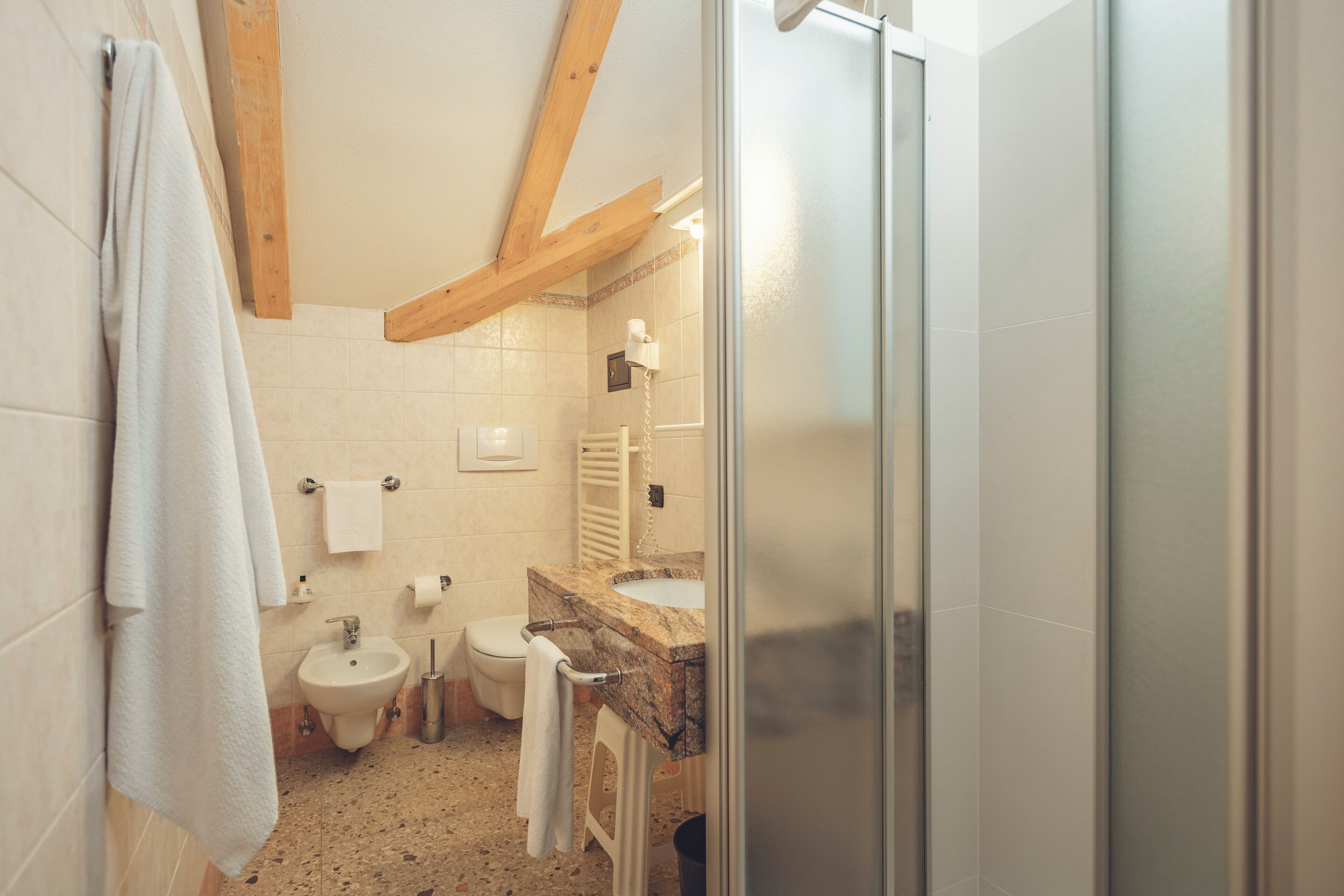 Un baño con lavamanos de mármol, un bidé, un inodoro y una puerta de ducha de vidrio.