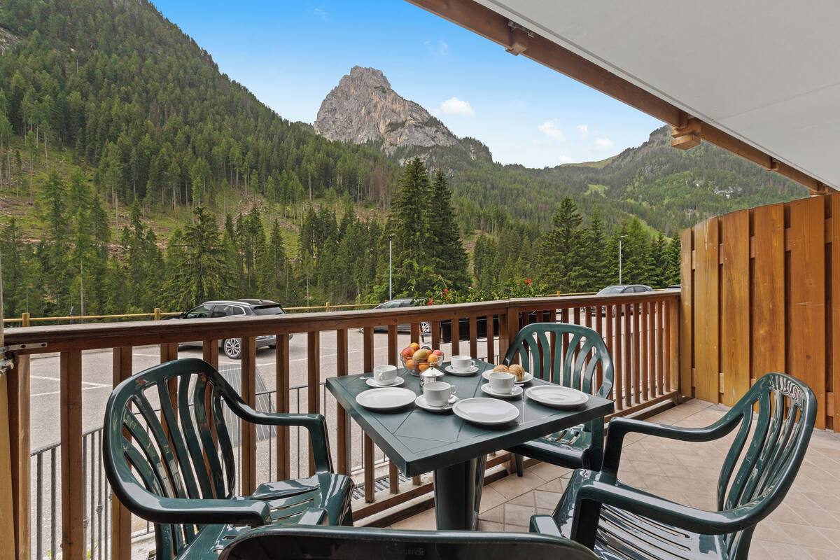 A balcony with a table set for breakfast, overlooking a mountainous landscape.