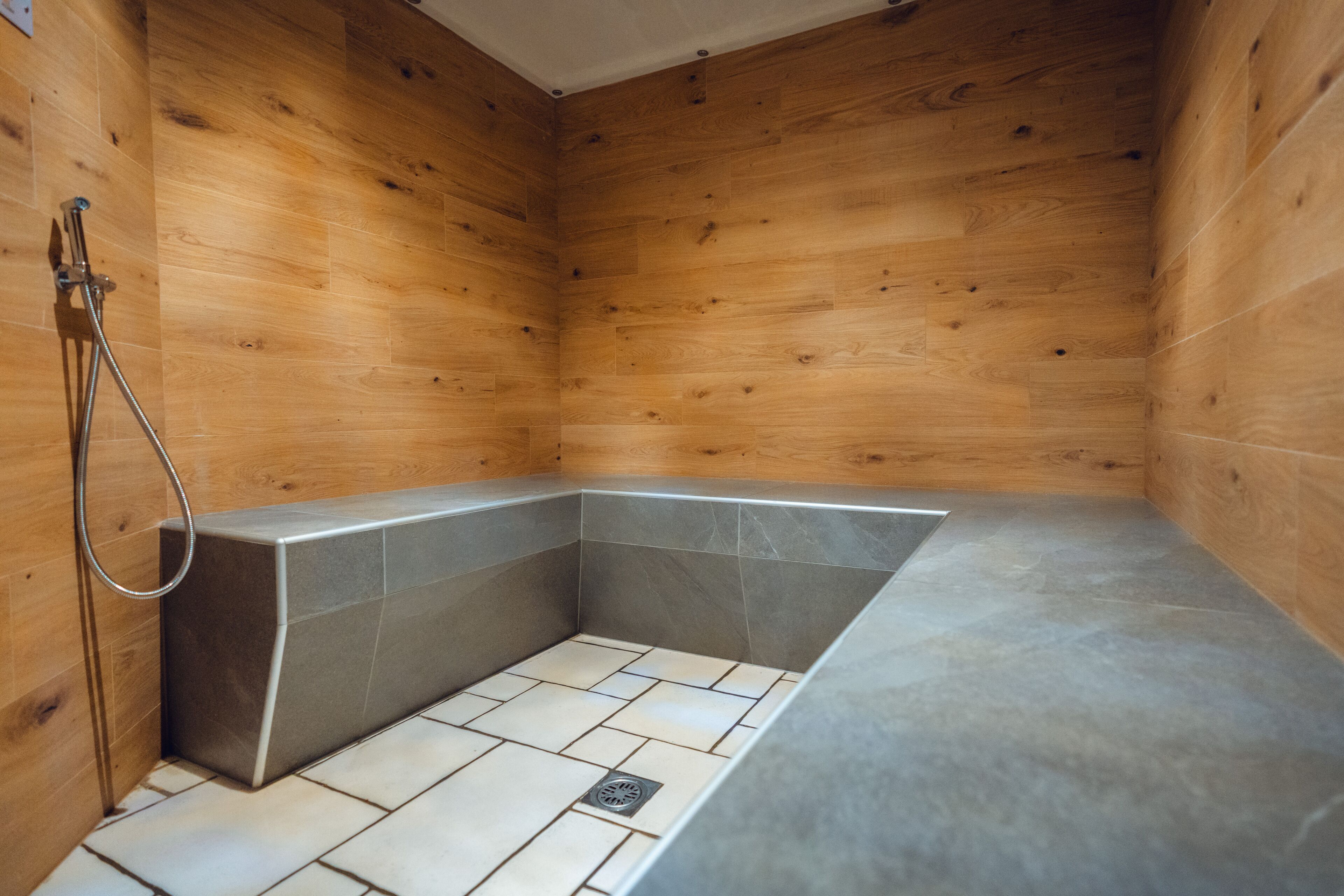A wooden-paneled shower room with a built-in bathtub and a showerhead.