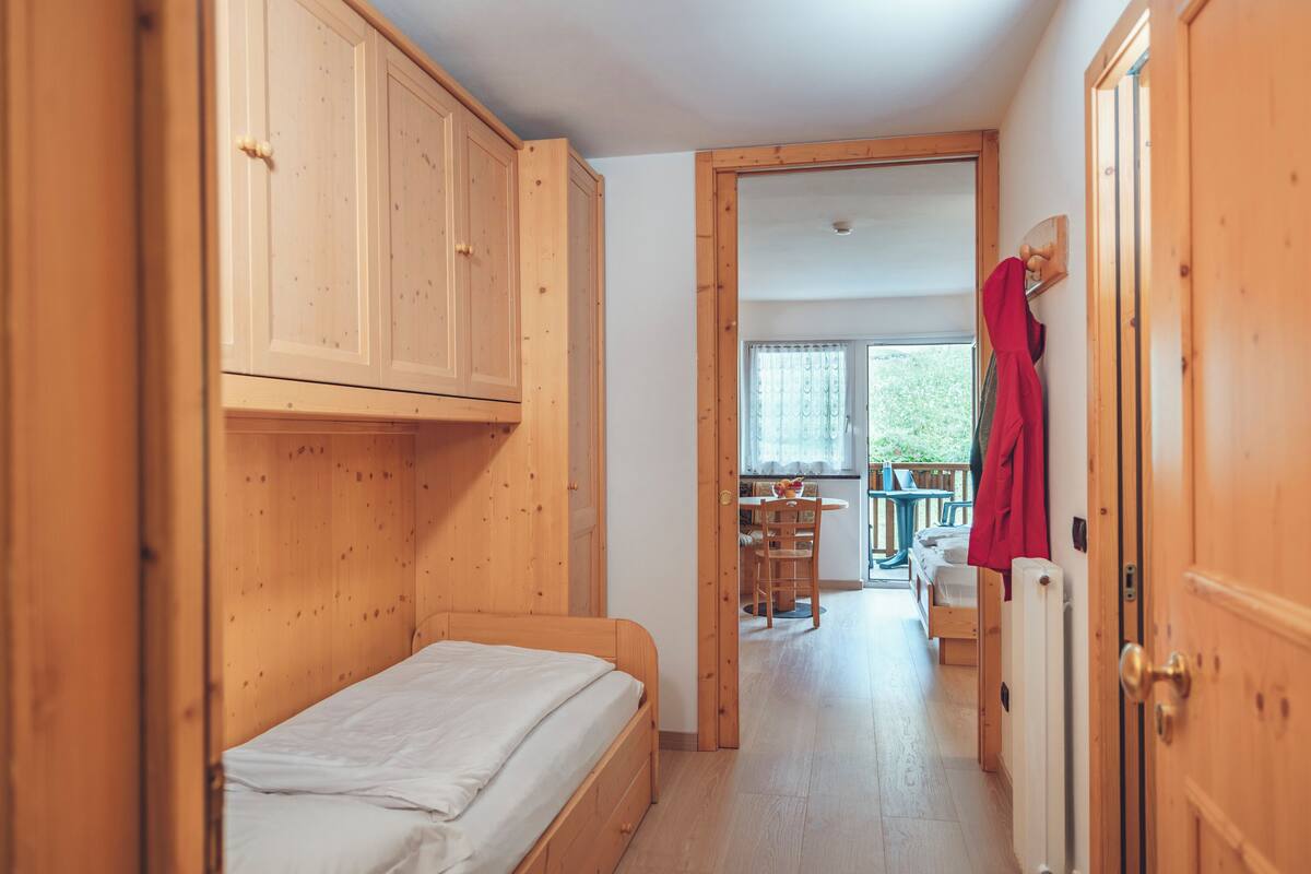 A wooden room with a bed, a table, and a chair.