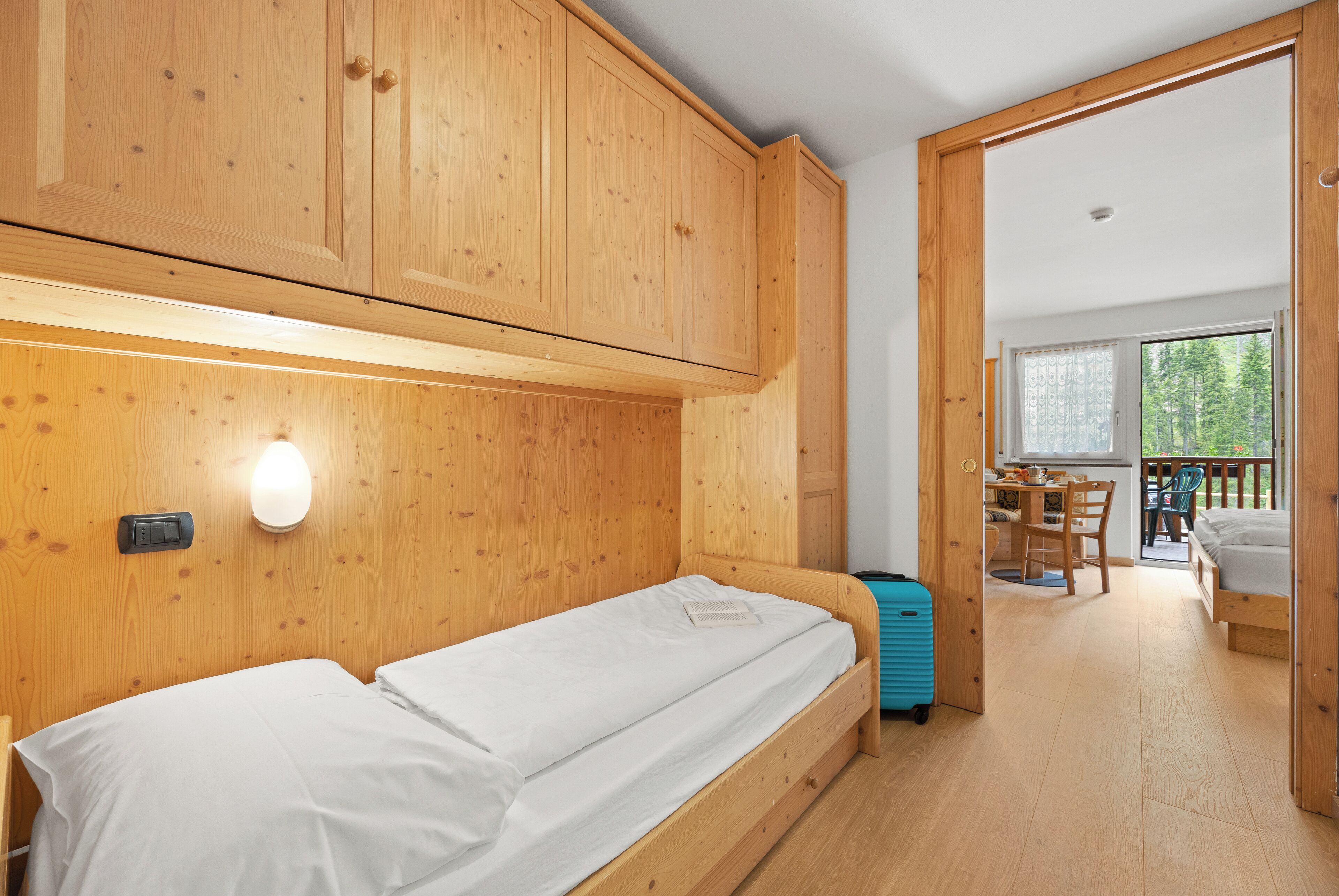 A wooden room with a bed, a desk, and a window.