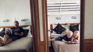 A cozy room with a bed, a reading area, and a bunk bed. - Nitmiluk Cabins (Nitmiluk)
