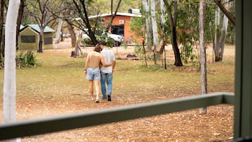 Una pareja caminando en un parque con árboles y un edificio al fondo.
