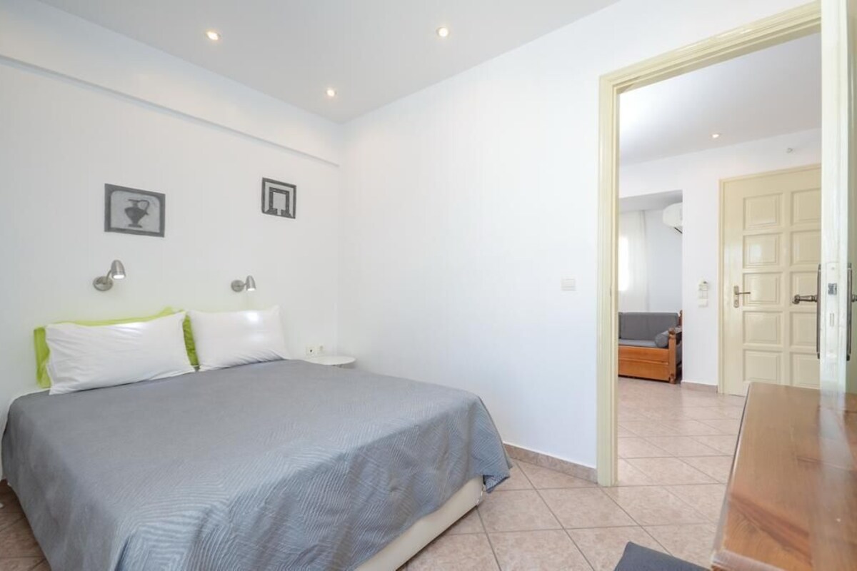 Une chambre à coucher avec un lit, des tables de chevet et une porte donnant sur une autre pièce.