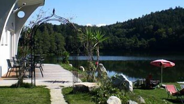 Une terrasse au bord du lac, aménagée avec du mobilier d’extérieur et offrant une vue sur le lac.
