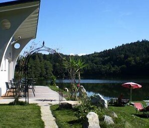 Une terrasse au bord du lac, aménagée avec du mobilier d’extérieur et offrant une vue sur le lac.
