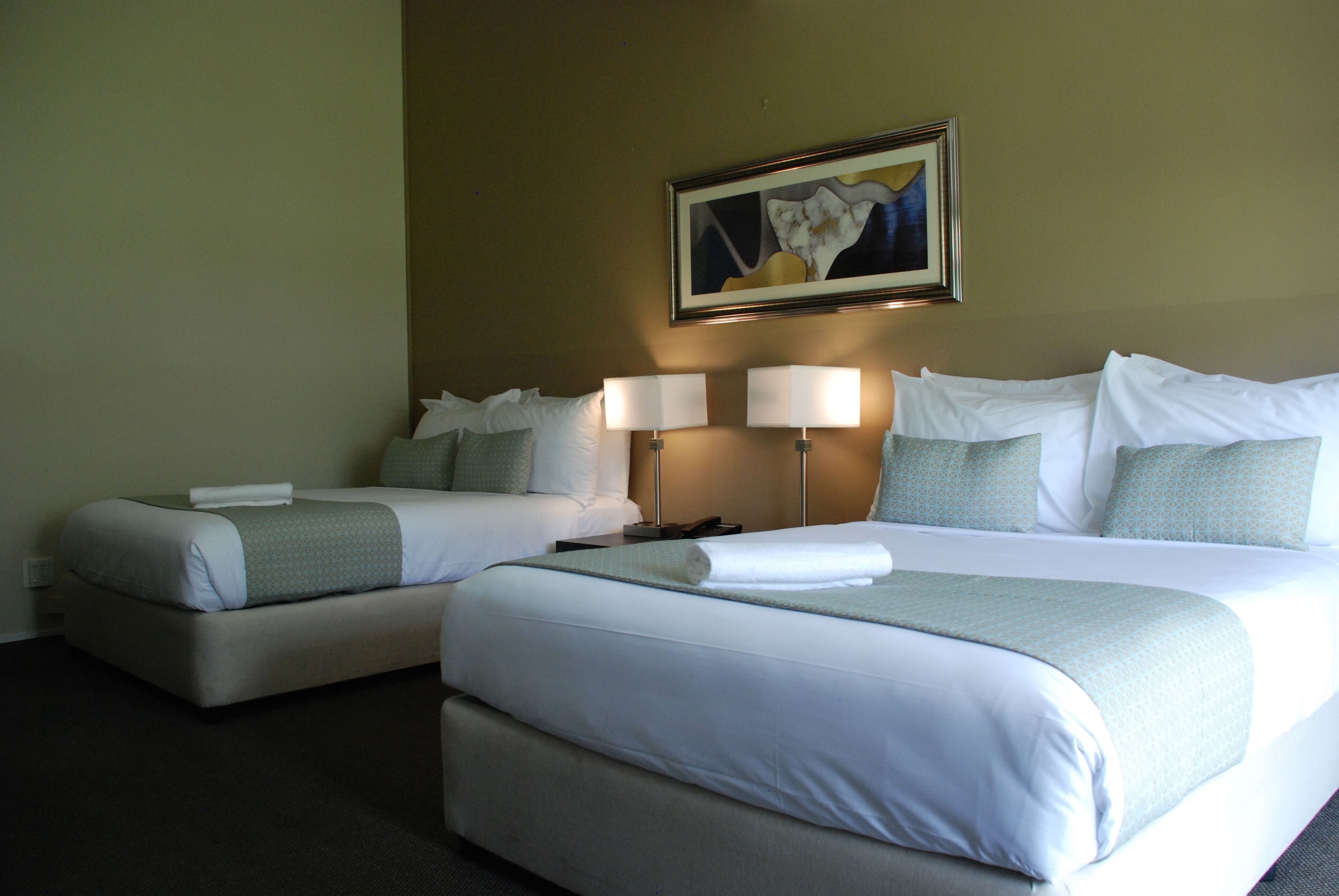Une chambre d’hôtel avec deux lits, chacun étant équipé d’un oreiller, d’une couverture et d’une table de chevet avec une lampe.