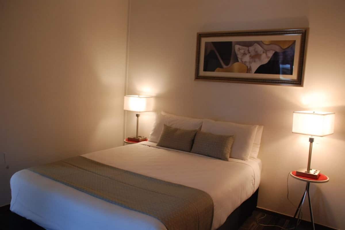 A hotel room with a large bed, two bedside tables with lamps, and a framed picture on the wall.