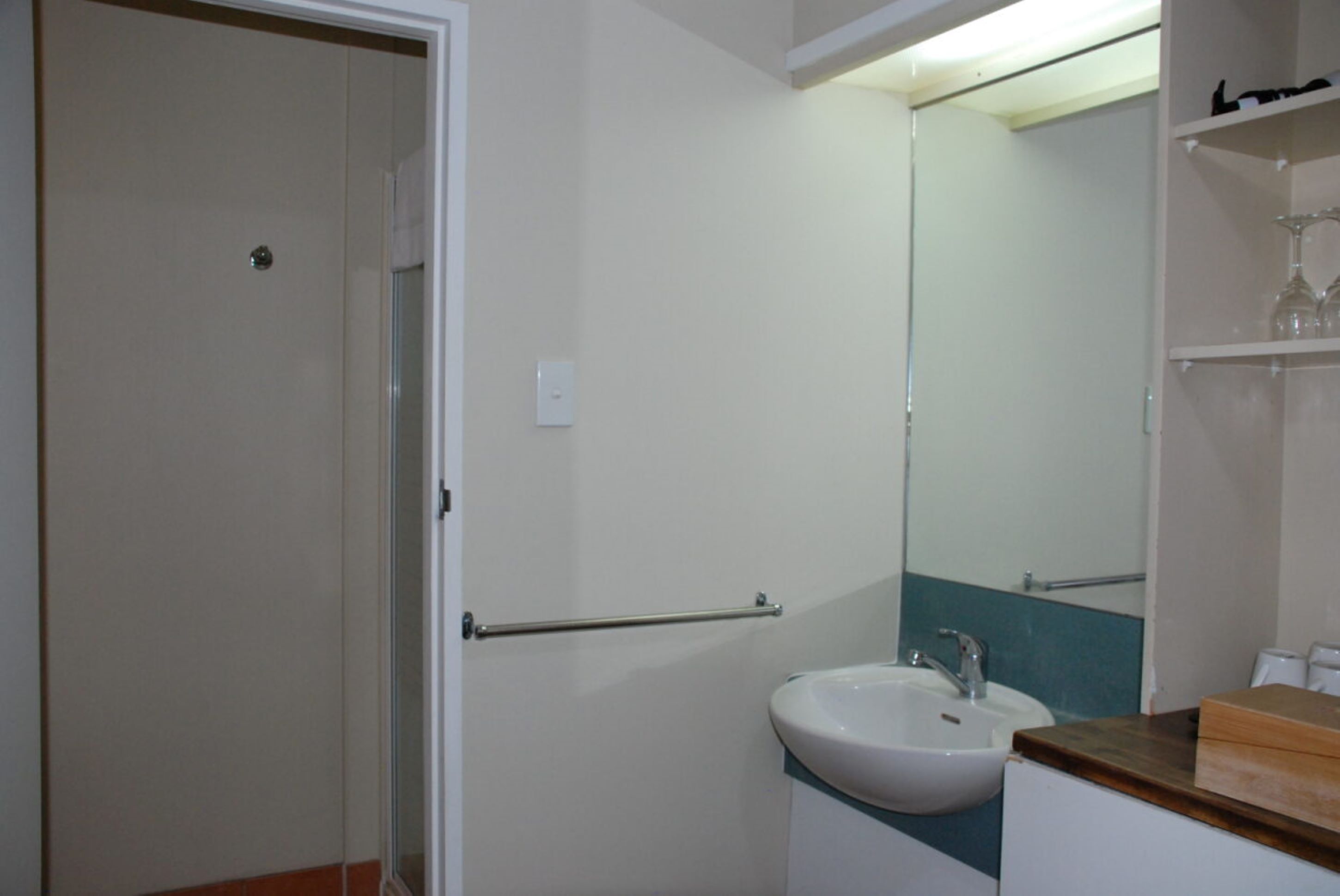 A bathroom with a white sink, a mirror, and a towel rack.