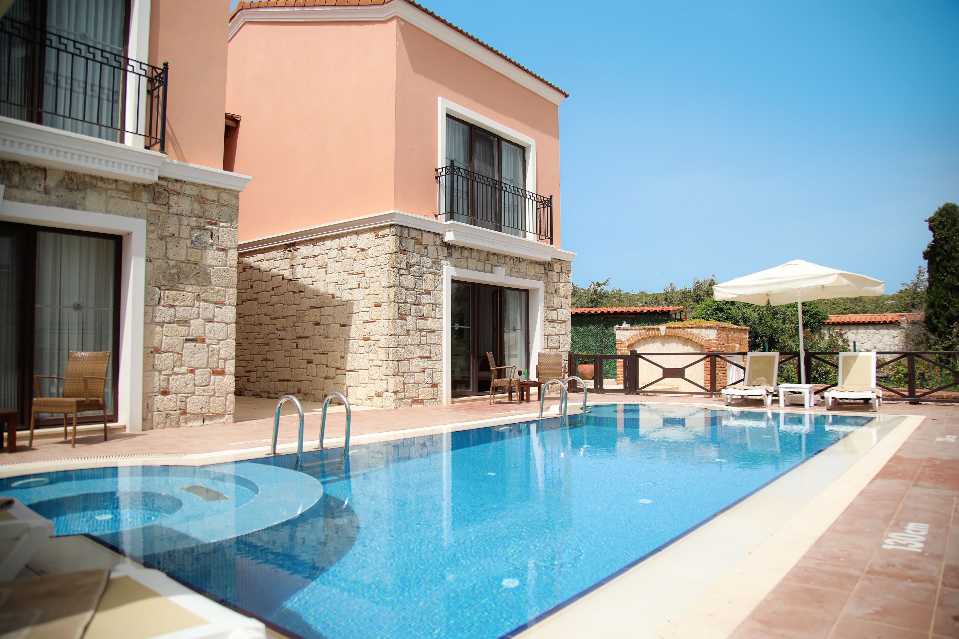 Una piscina con sillones de descanso y un muro de piedra.