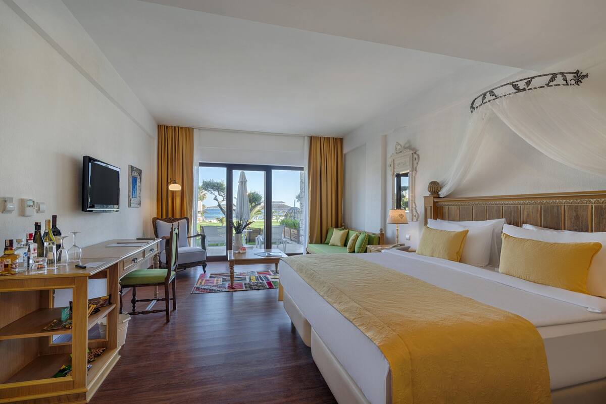 Une chambre d’hôtel équipée d’un lit, d’un bureau, d’une chaise, d’une télévision et offrant une vue sur l’extérieur.
