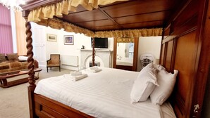 A neatly made bed with white linens, a wooden headboard, and a canopy. There is a chair and a small table in the room. - The Guards Hotel (Edinburgh)