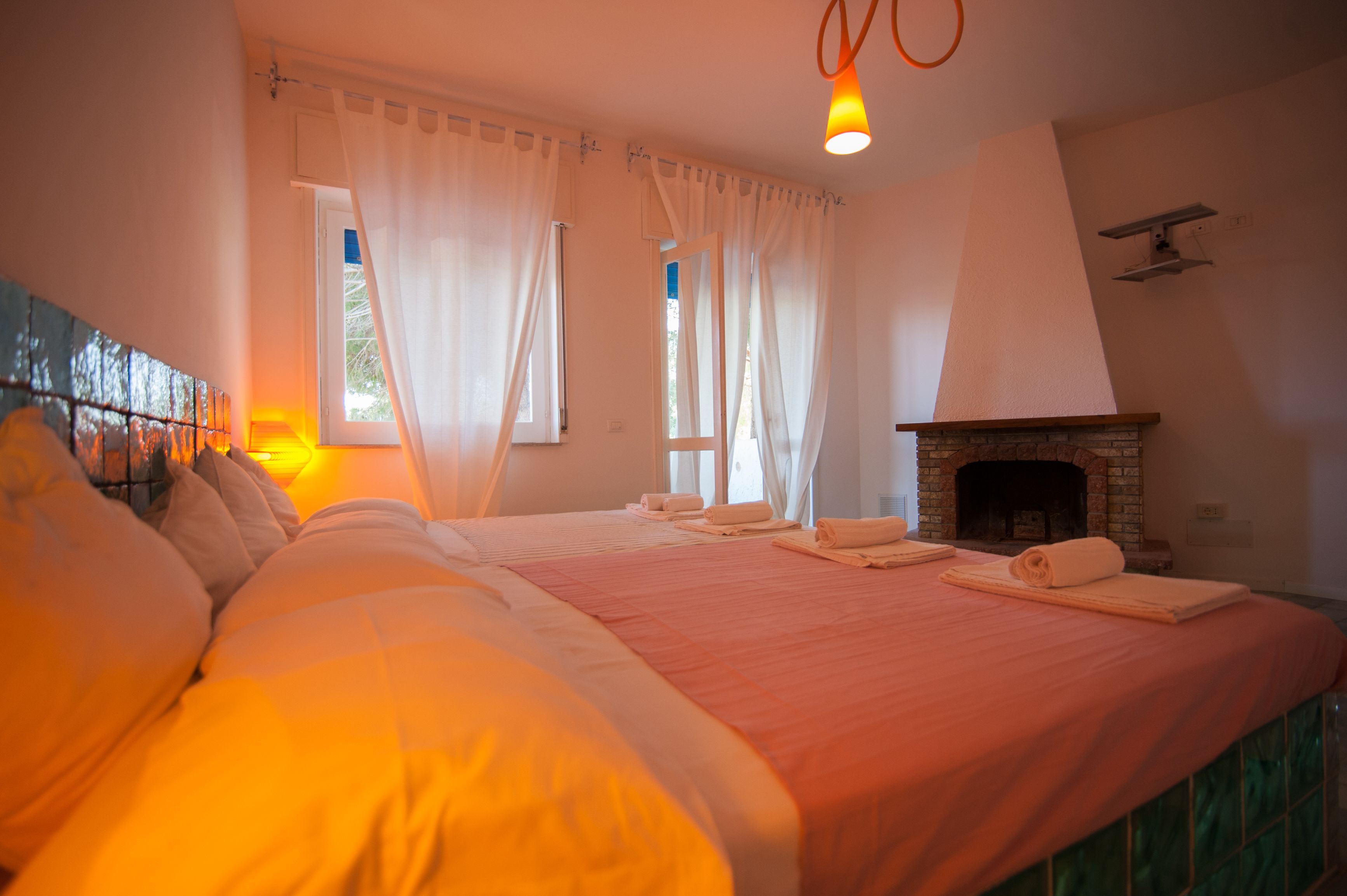 Un dormitorio con dos camas, una chimenea y un ventanal con cortinas.