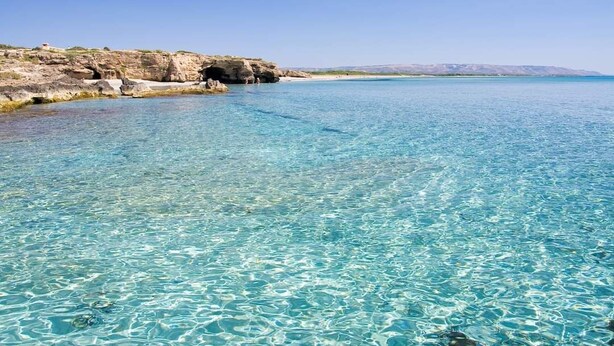 A clear blue sea with rocky cliffs and a sandy beach. - Suite House L'isola che non c'è (Syracuse)