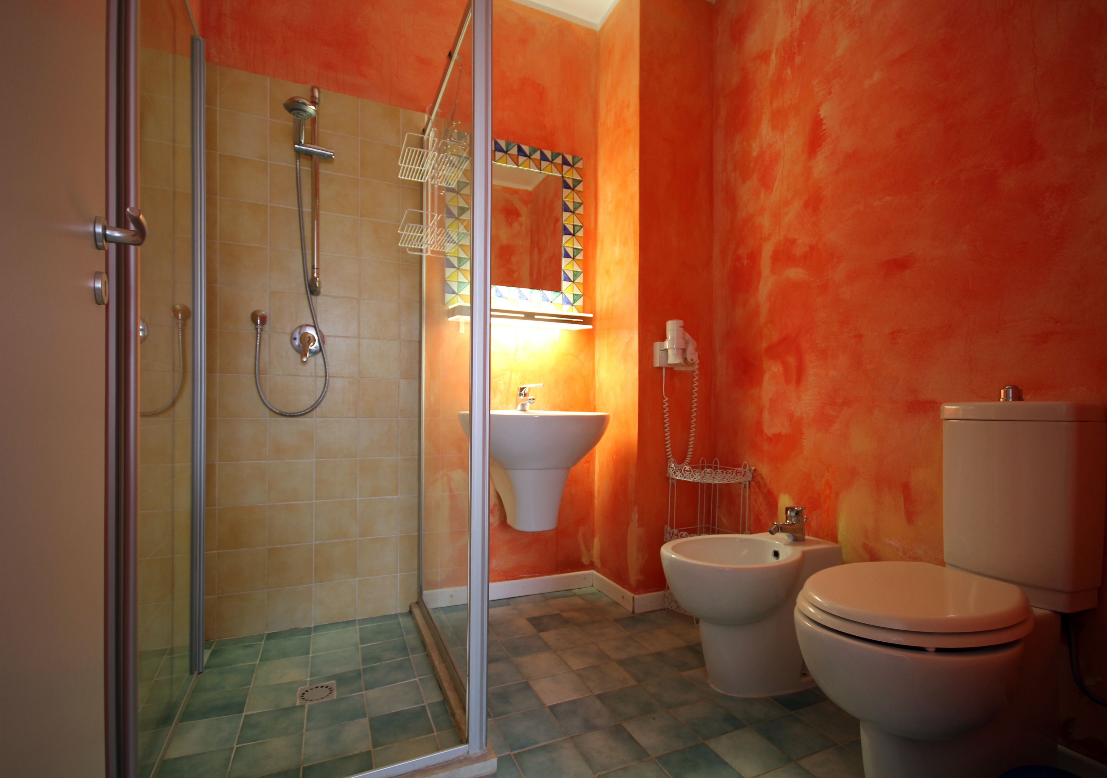 Baño con ducha, lavabo, inodoro y espejo con detalles de azulejos geométricos.